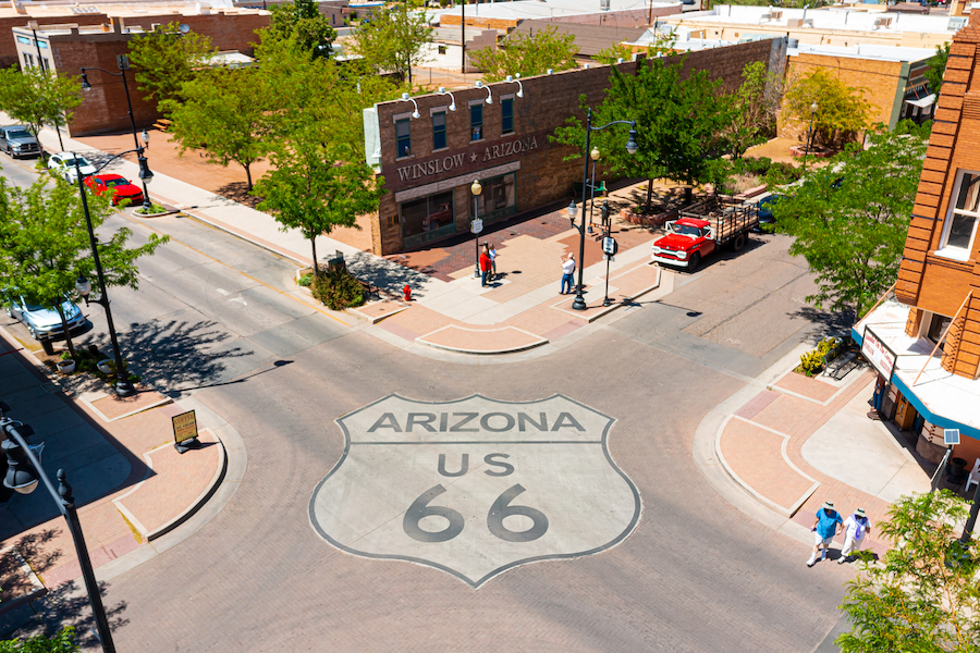 An aerial view of an intersection in the town of Winslow, with the Route 66 logo painted on the road — a small town with character, debunking the meeting myth that business meetings need to be held in big cities.